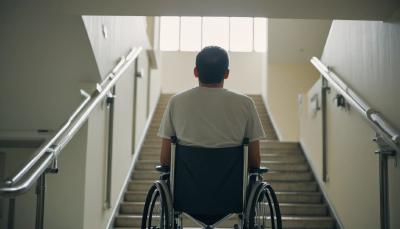 A man in a wheelchair halfway on a stairway